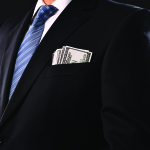 Money in businessman's pocket. Black background.
